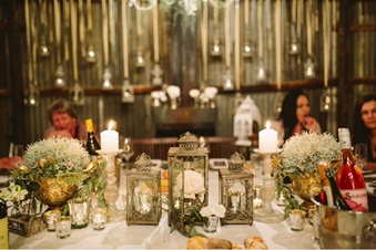 Vintage style lanterns with metal candlesticks and old gold urn planters were used as centerpieces on the main table 